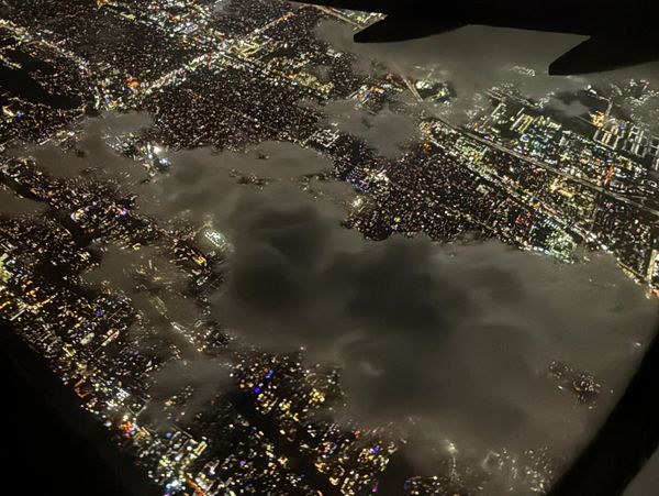 Aerial night view of a city with illuminated streets and clouds.