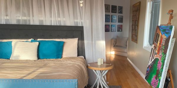 Cozy bedroom with blue accents and an easel displaying a colorful painting.