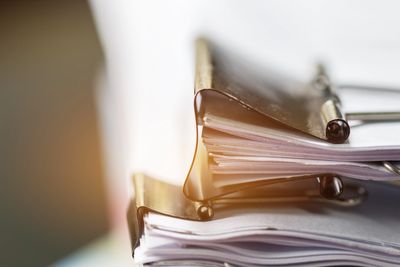 Close-up of two thick stacks of paper clipped with binder clips.