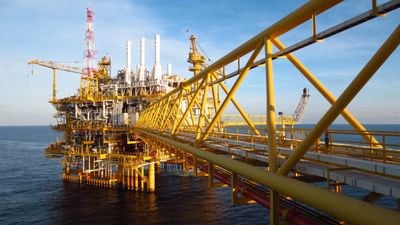 A yellow offshore oil platform over the ocean during daytime.
