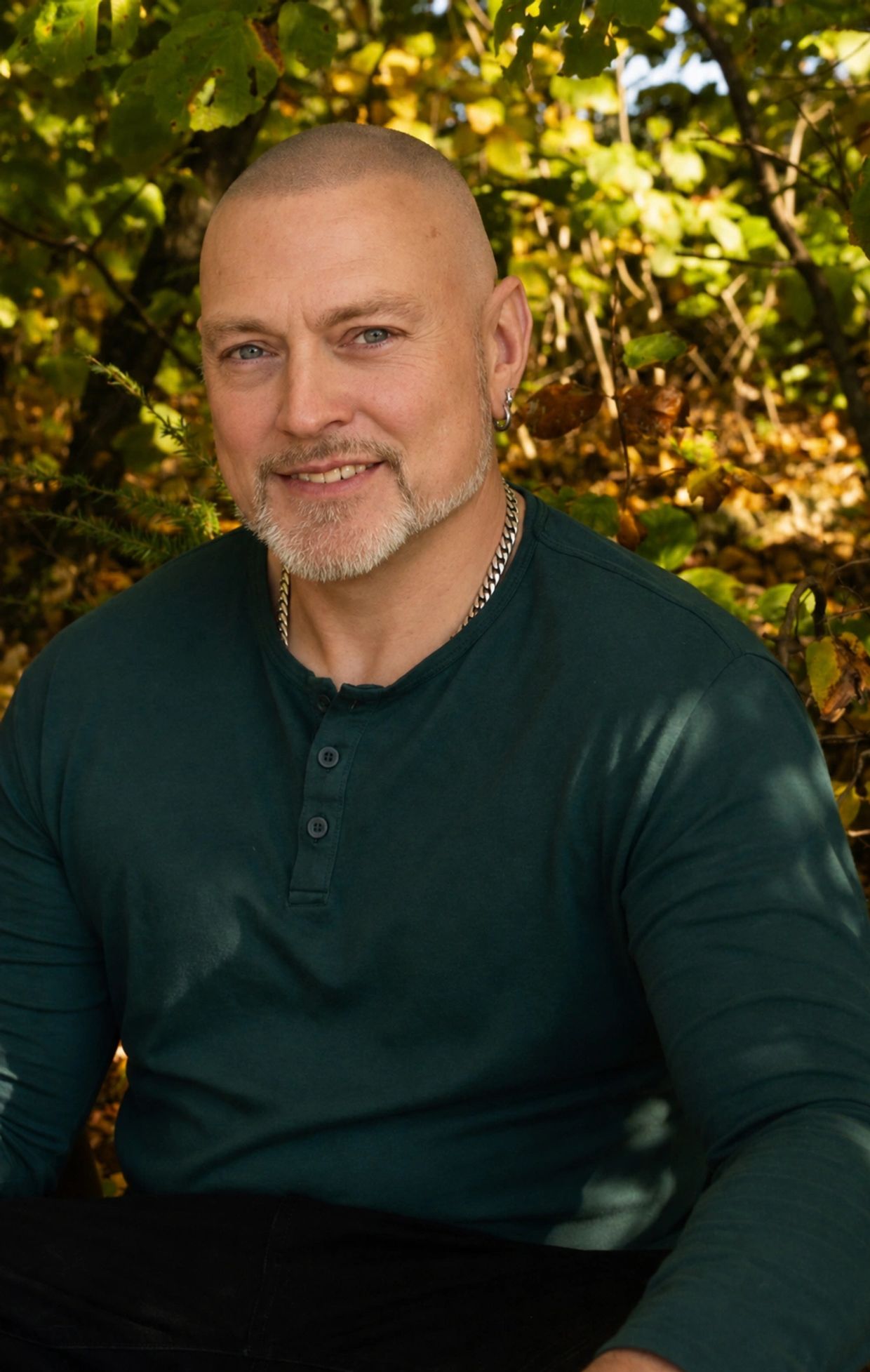 Smiling bald man with a beard outdoors.