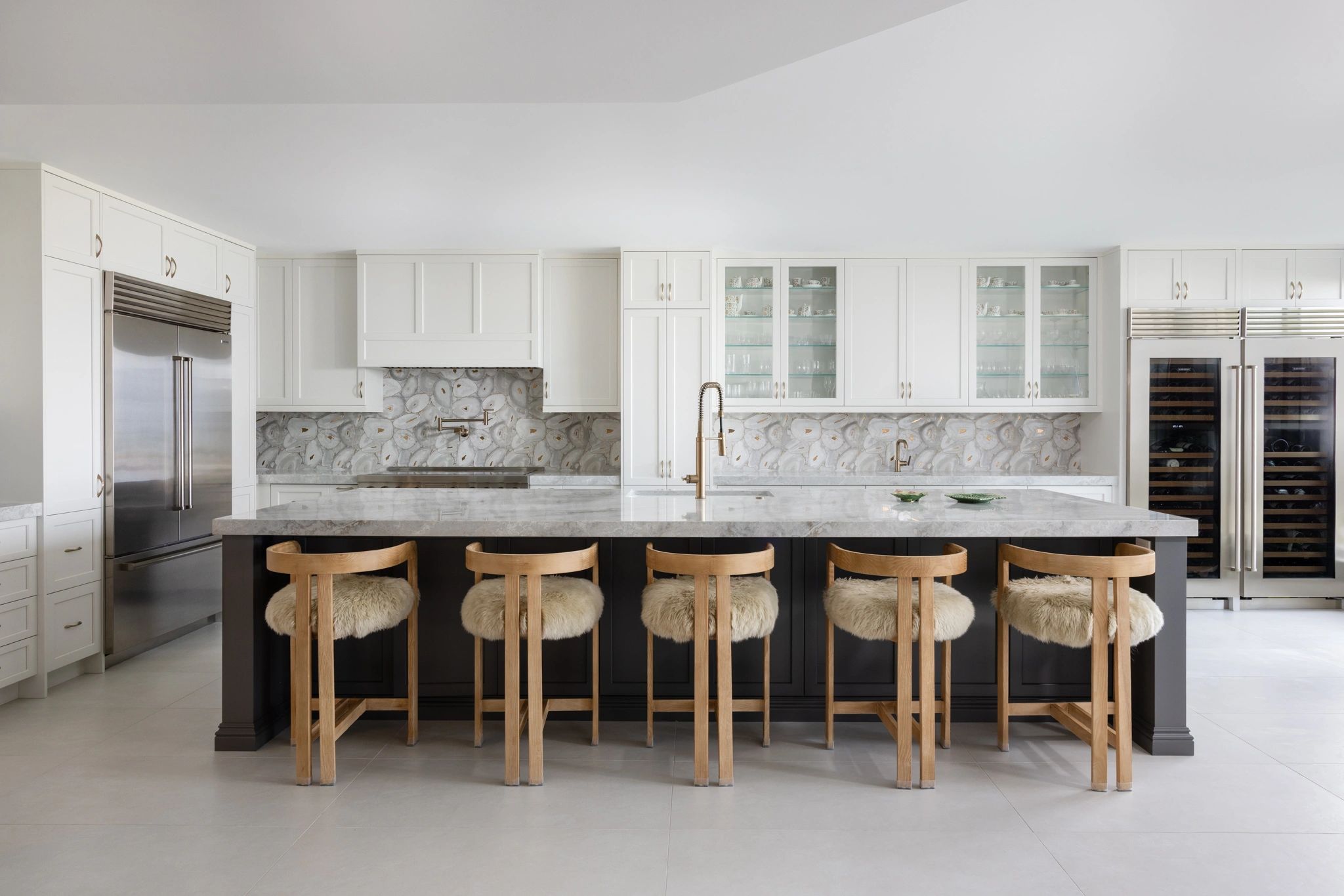 Modern kitchen with marble island and wooden bar stools.