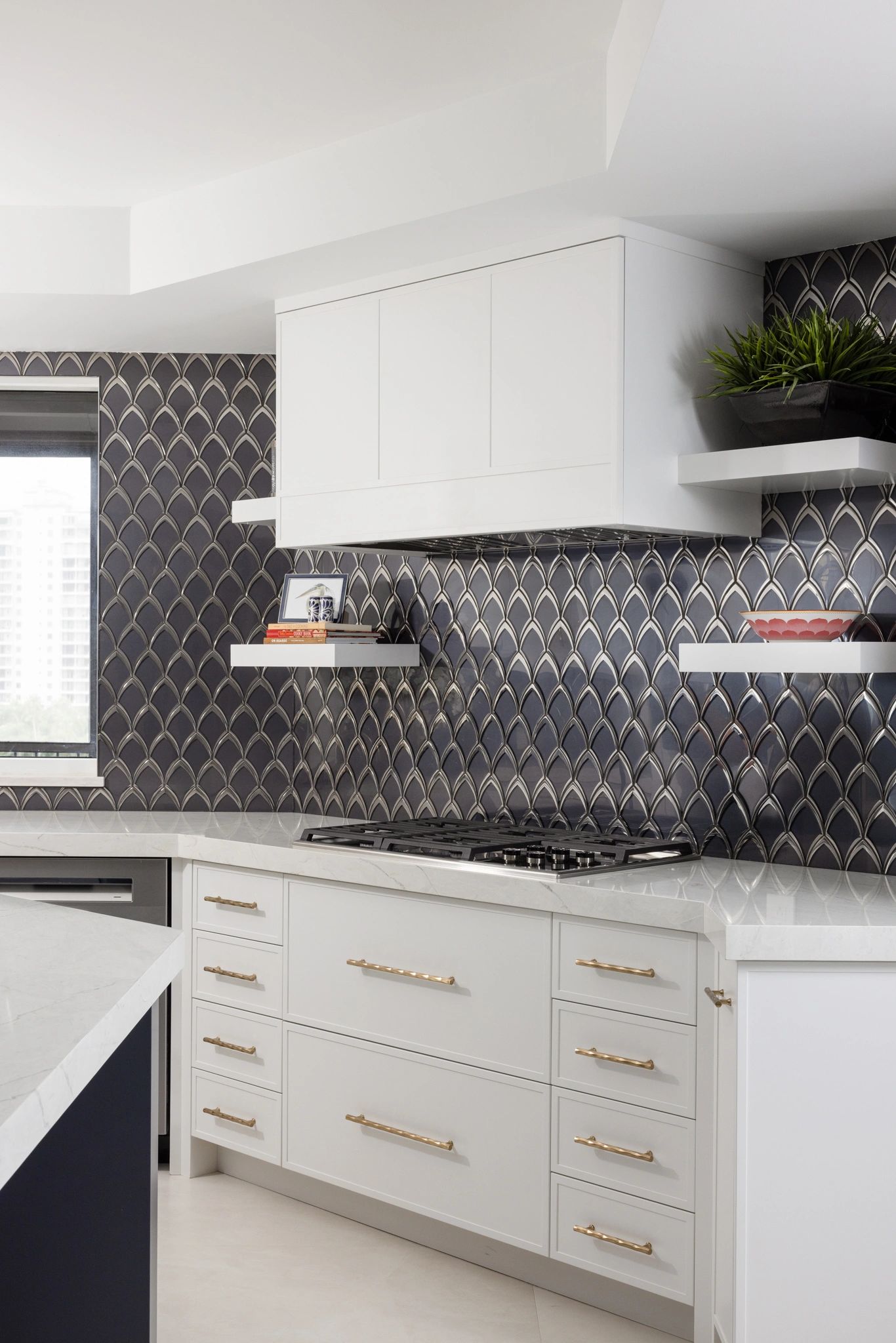 Modern kitchen with white cabinets and dark patterned backsplash.