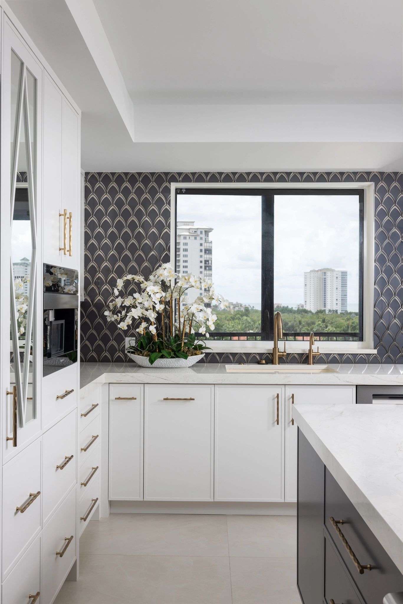 Modern kitchen with white cabinets and dark patterned backsplash.