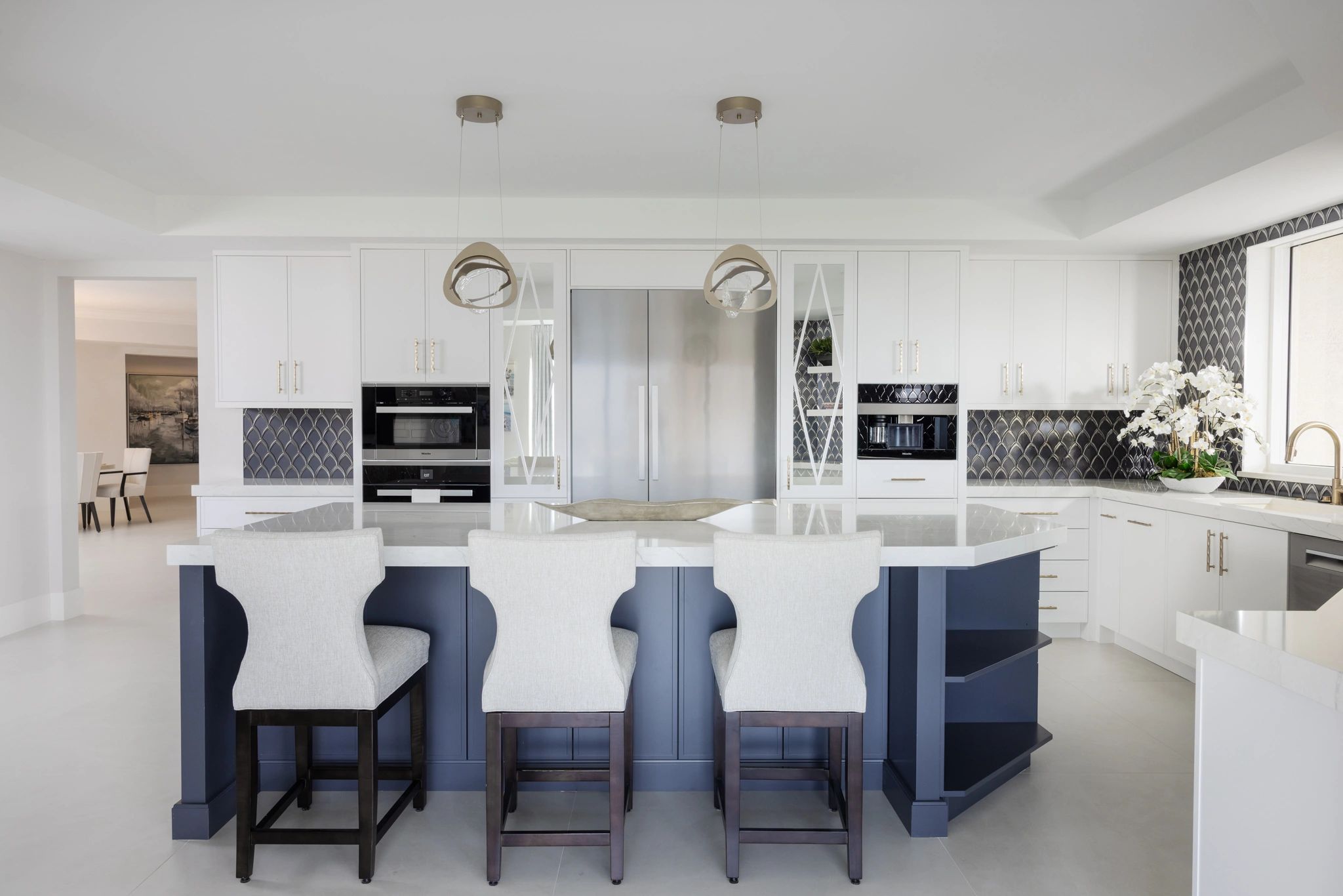 Modern kitchen with navy island and white cabinets.