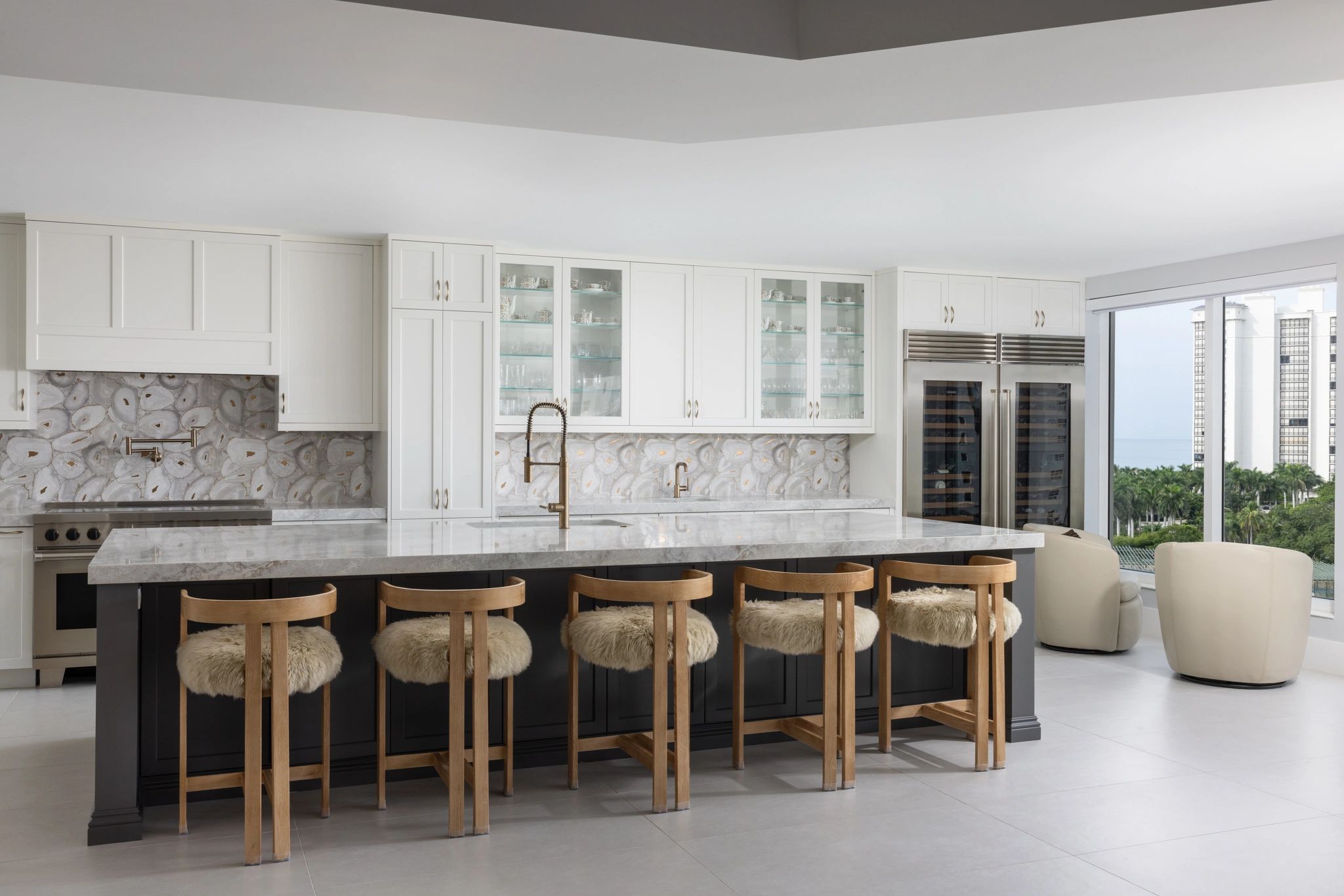 Modern kitchen with marble island and wooden fuzzy stools.