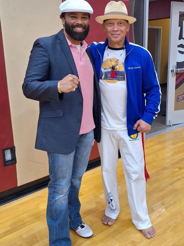 Two men posing together, one in casual blazer and the other in martial arts attire.