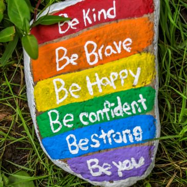 Colorful rock with motivational phrases painted on it.
