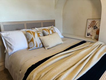 Cozy bed with patterned pillows and warm blankets in a softly lit room.