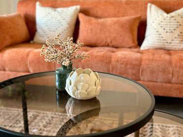 Cozy living room with a glass coffee table and decorative items.