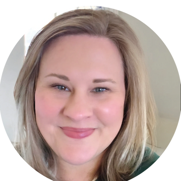 Smiling woman with blonde hair and light makeup in a softly lit room.