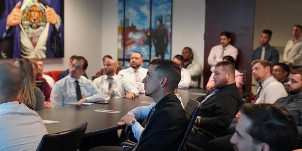 Group of men attentively listening in a formal meeting room.