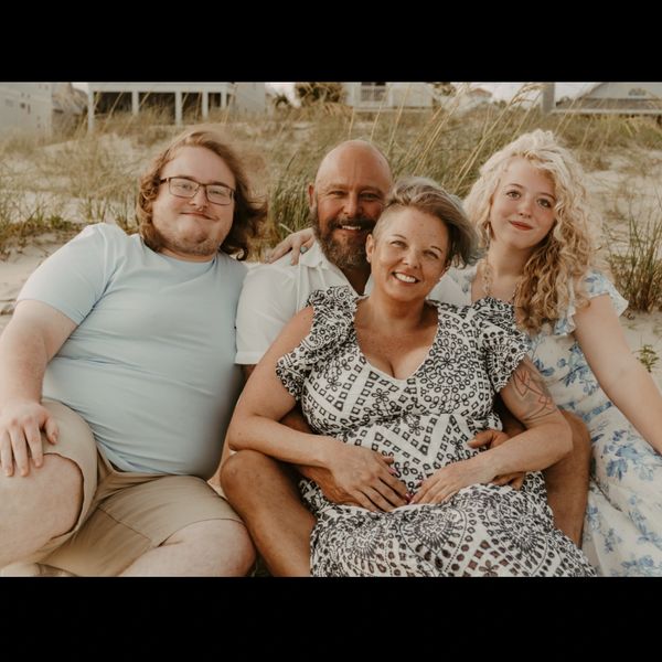Family sitting together on a beach during sunset.