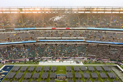 Military personnel organized on a football field at a large stadium event.