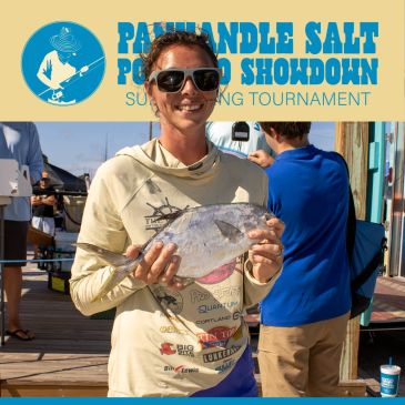 Man holding a fish at a fishing tournament.