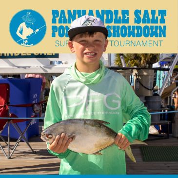 Boy holding a fish at a fishing tournament.