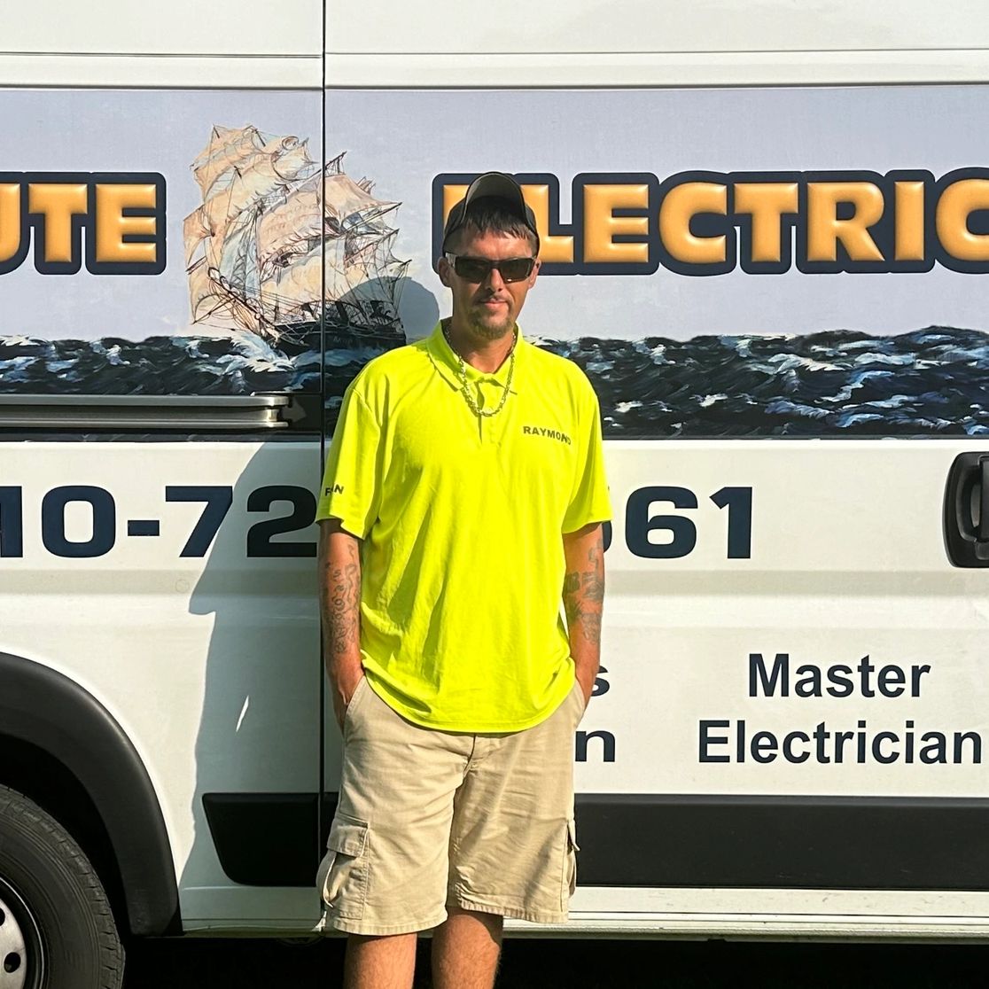 Man in bright yellow shirt standing in front of an electrician van.