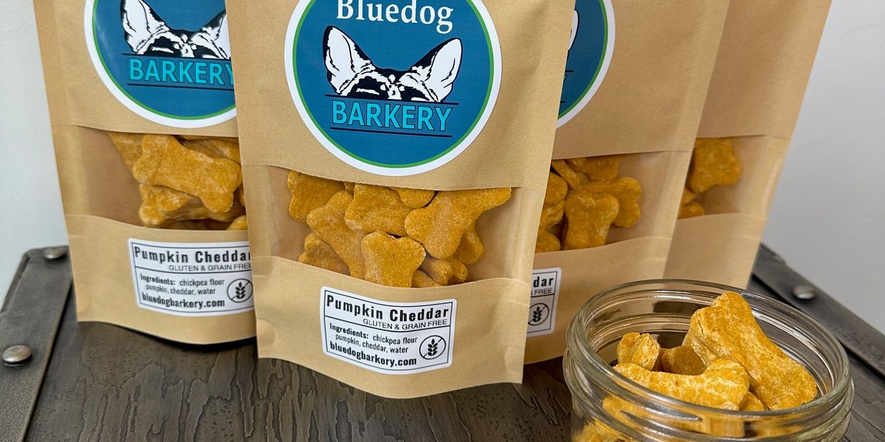Pumpkin cheddar dog treats in bags and a jar.