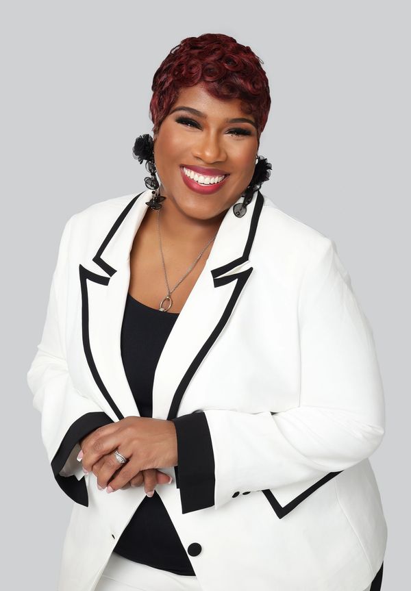 Smiling woman in a white blazer with black accents.