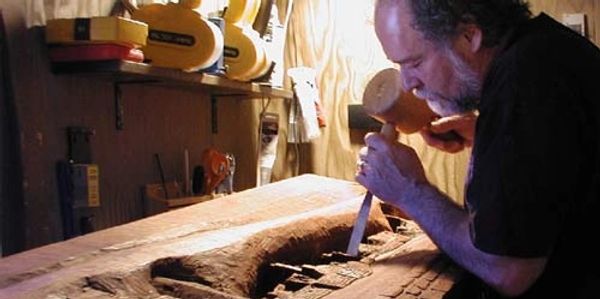 Colorado artist Carl Bandy carving a Mahogany sculpture used in making a handmade cast paper sculpture.