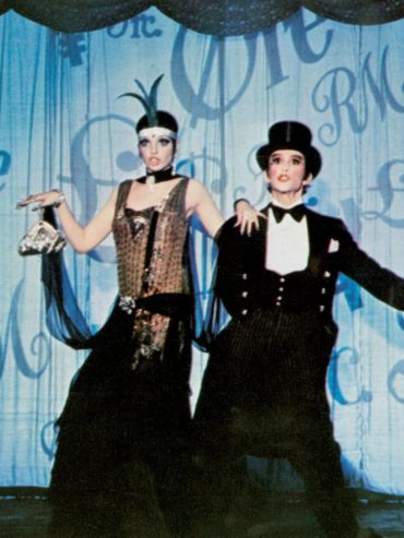 Two performers in vintage cabaret costumes on stage.