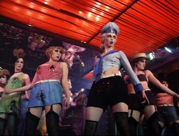 Women dancing in stylish outfits under red lighting.