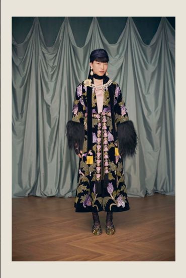 Fashion model in floral embroidered coat with fur cuffs.