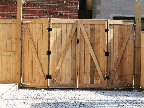 Wooden double gates with diagonal braces and black metal hinges.