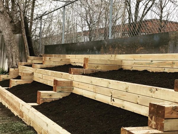 Newly built wooden tiered garden beds filled with soil.