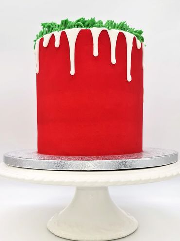 Red cake with a white drip and green buttercream grass. 