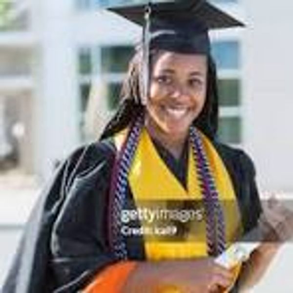 Smiling graduate in cap and gown holding diploma outdoors.