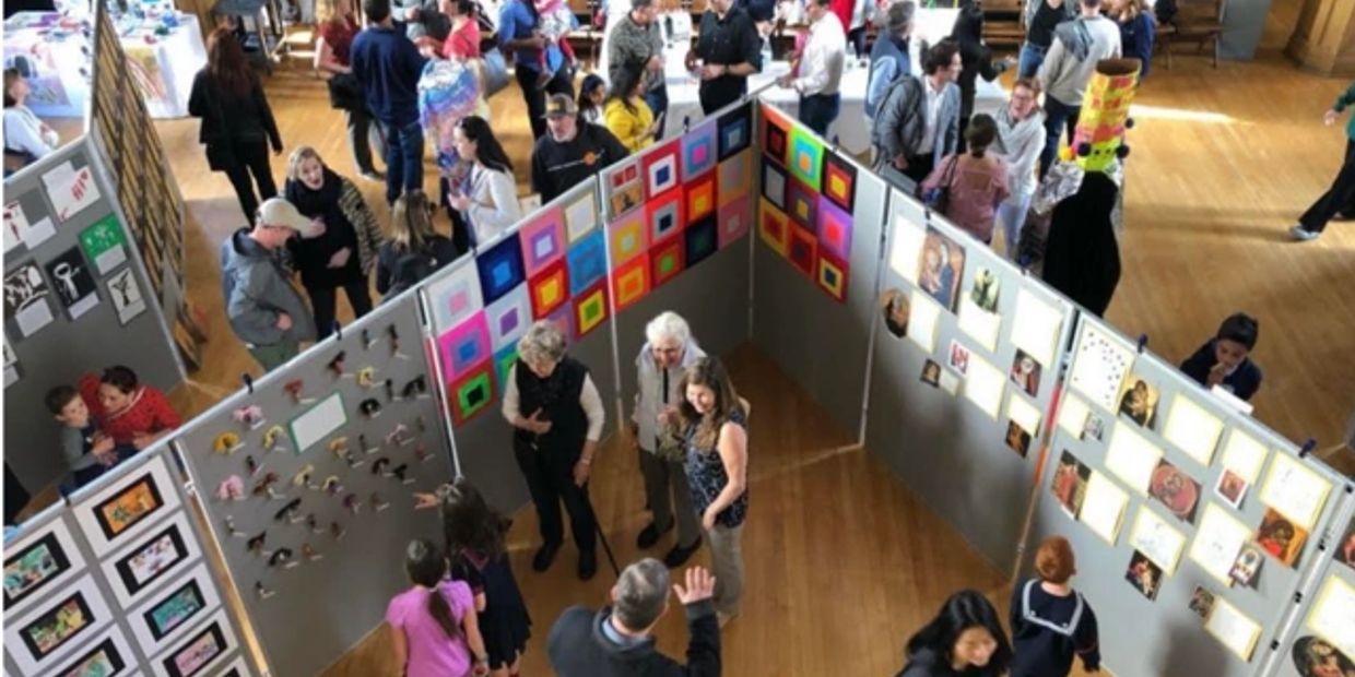 People exploring colorful art displays in a lively exhibition hall.