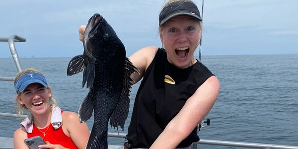 Woman Holding Black Sea Bass enthusiastically with other woman smiling