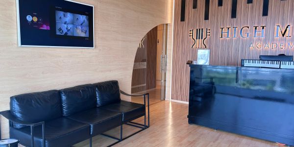 Recepción con sofá negro y televisor en la pared.