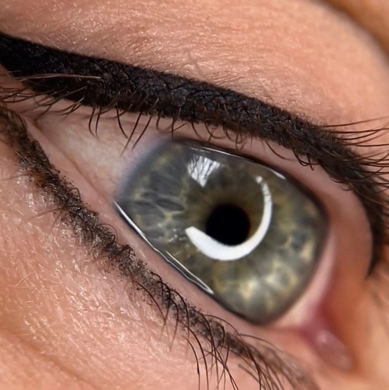 Close-up of a green eye with detailed eyeliner and lashes.