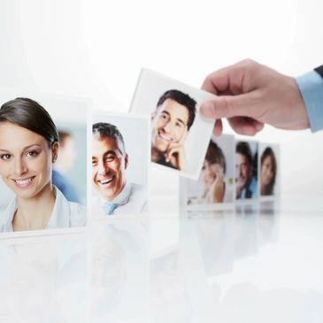 Hand selecting a smiling man's photo from a lineup of professional portraits.