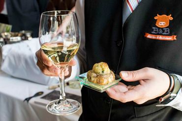 Waiter at B & B Butcher serving white wine and appetizer to a guest