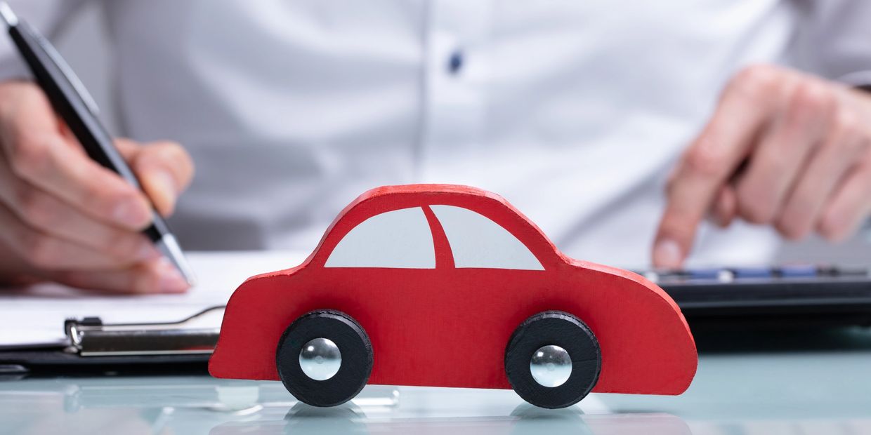 red toy car on table in front of business man with calculator