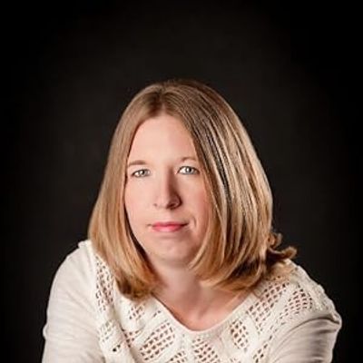 Portrait of a woman with shoulder-length blonde hair against a black background.
