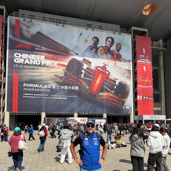 Man posing in front of a large Formula 1 Chinese Grand Prix banner at Shanghai International Circuit.