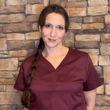 picture of lady with brown hair in a braided pony tail wearing a maroon scrub top