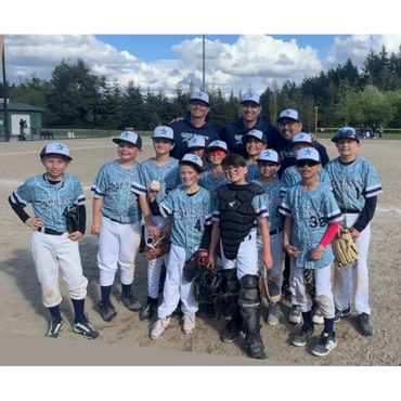 Youth baseball team posing together on the field in matching uniforms.