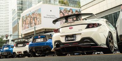 Rear view of sporty cars parked in a city setting with skyscrapers.