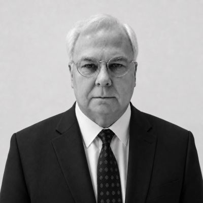 Serious older man in a suit and glasses.
