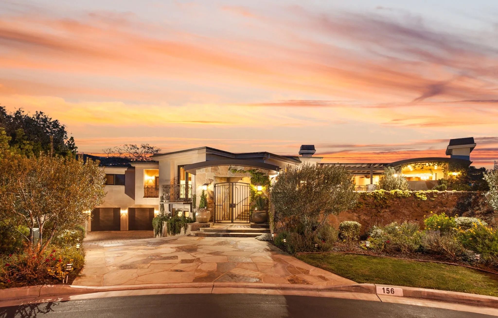 Luxurious modern house at sunset with warm lighting and lush landscaping.