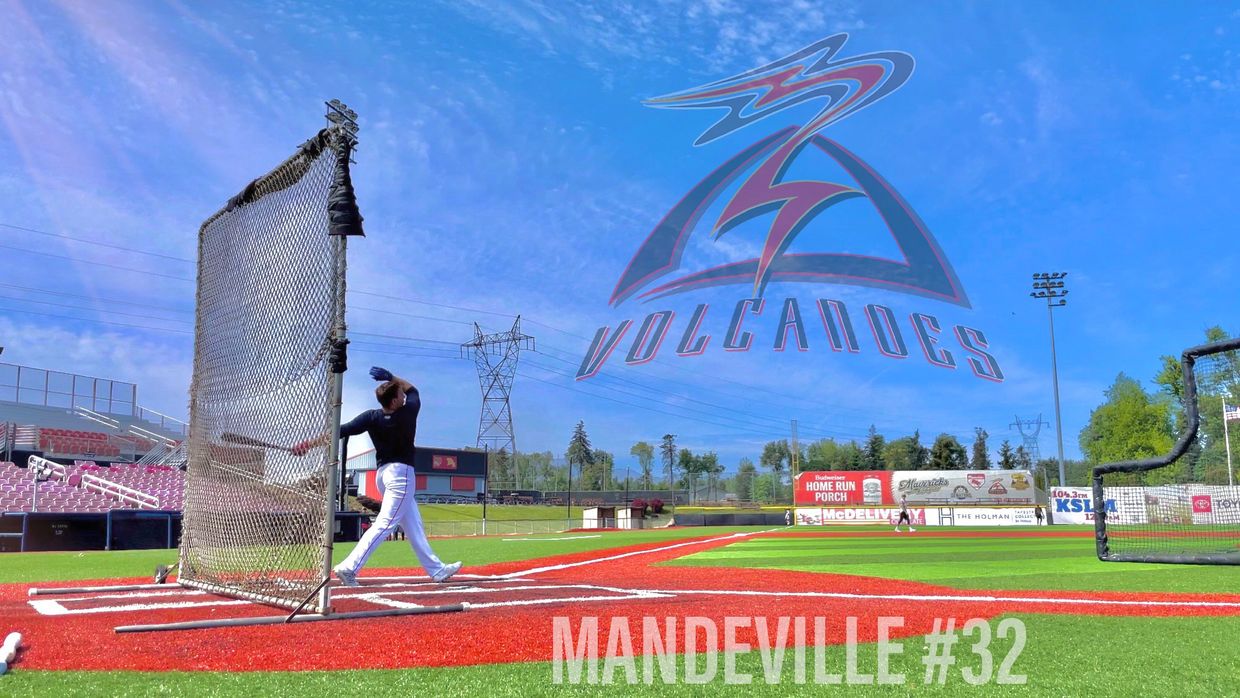 Baseball player Mandeville swings at a pitch on a sunny day at Volcanoes stadium.