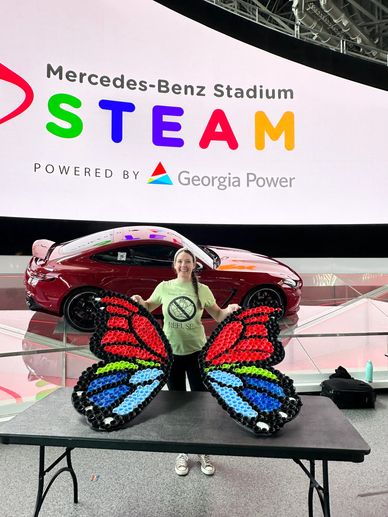 Person showing butterfly wings made of balloons at Mercedes-Benz Stadium.