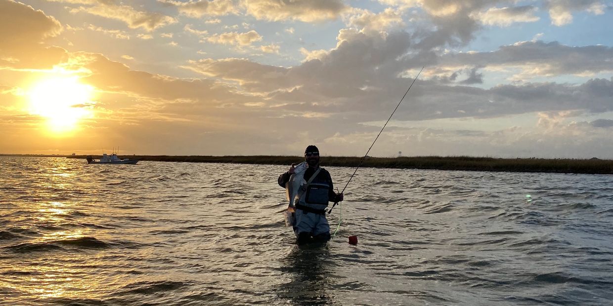 A man is fishing in the waters of Galveston, Texas.