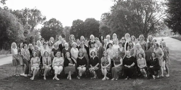 Large group of women posing outdoors in black and white photo.
