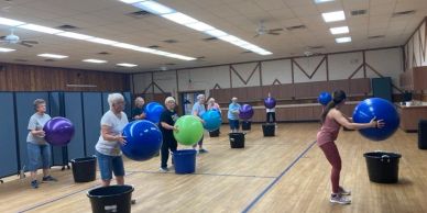 People exercising with large colored balls in a gym.